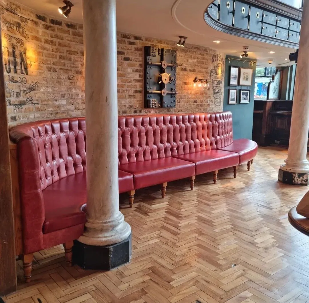 Long red chesterfield banquette in a bar interior